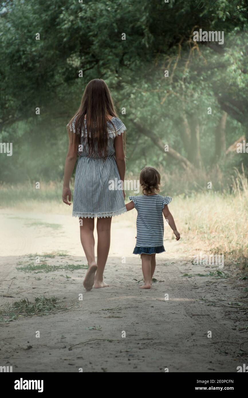 La sœur aînée marche avec sa sœur plus jeune dans la nature. Banque D'Images