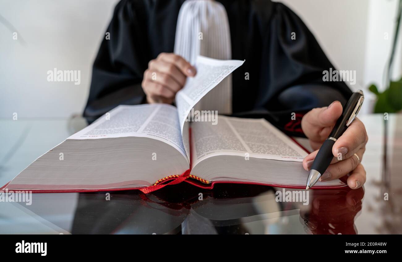 Justice, avocate femme tenant et lisant un livre rouge ouvert - droit français Banque D'Images