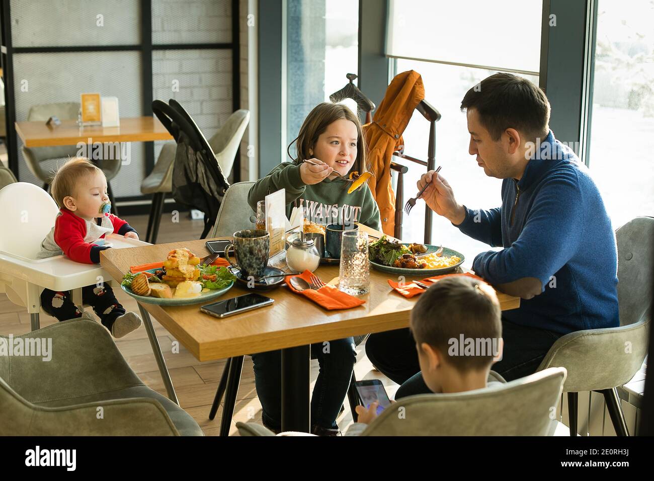 Une jeune famille prend le petit déjeuner dans un café de la ville. Fête des pères. Papa avec des enfants. Concept de style de vie Banque D'Images