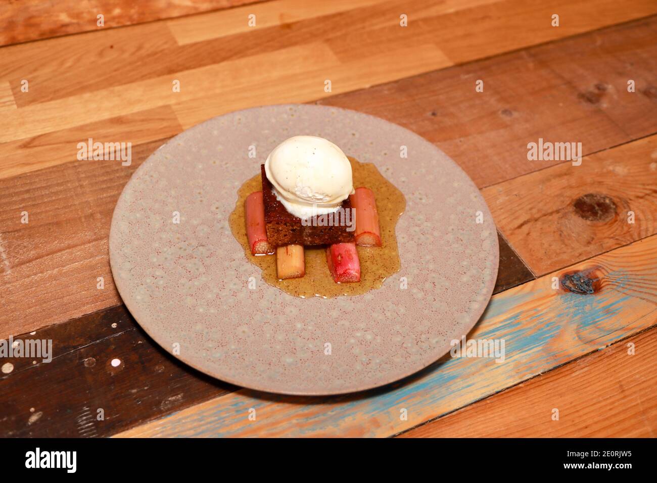 Une assiette de parkine traditionnel avec rhubarbe du yorkshire et glace crème sur fond de bois dans une cuisine Banque D'Images