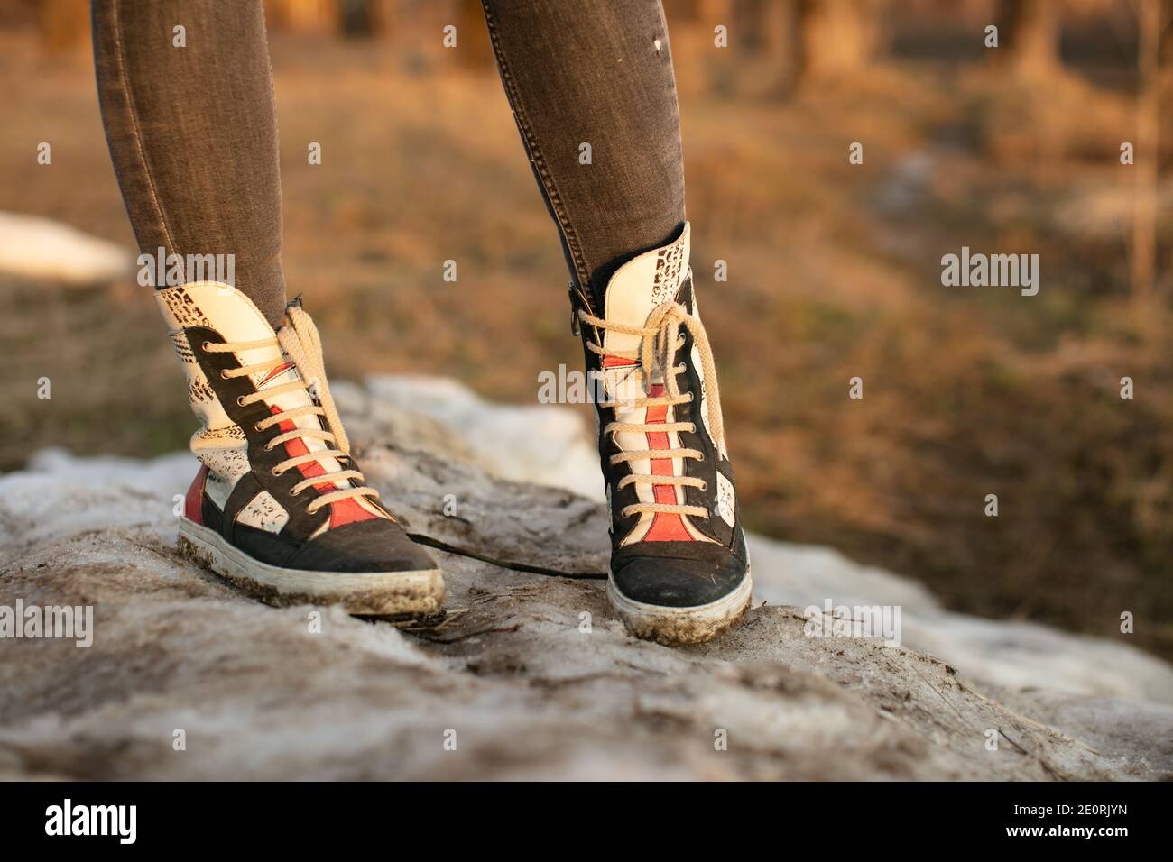 Baskets mode pour femme en cuir brillant et bottes en caoutchouc blanc  portées avec un Jean et les deux pieds orientés vers l'avant Photo Stock -  Alamy