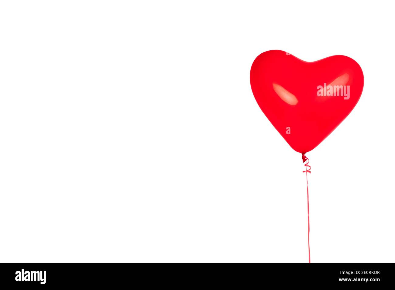 Un ballon en caoutchouc rouge vif en forme de coeur isolé sur fond blanc. Carte postale concept pour la Saint-Valentin 14 février ou amour, espace copie. Banque D'Images