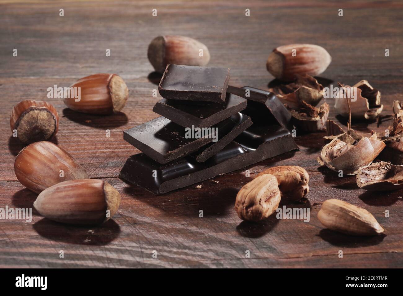 Chocolat noir et noisettes. Barre de chocolat cassée sur la table de cuisine noire Banque D'Images
