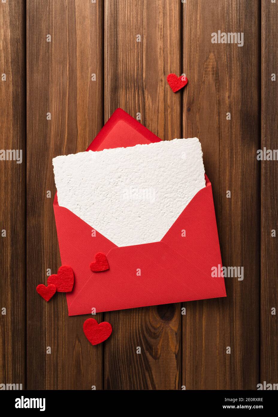 Historique de la Saint-Valentin avec modèle de carte de vœux dans l'enveloppe une table en bois vintage et des coeurs rouges Banque D'Images