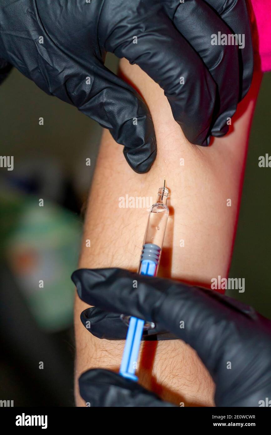 Covid-19: La main d'une infirmière avec des personnes noires injecte un vaccin contre Covid-19 (SRAS-COV-2) dans le bras d'un enfant. Banque D'Images