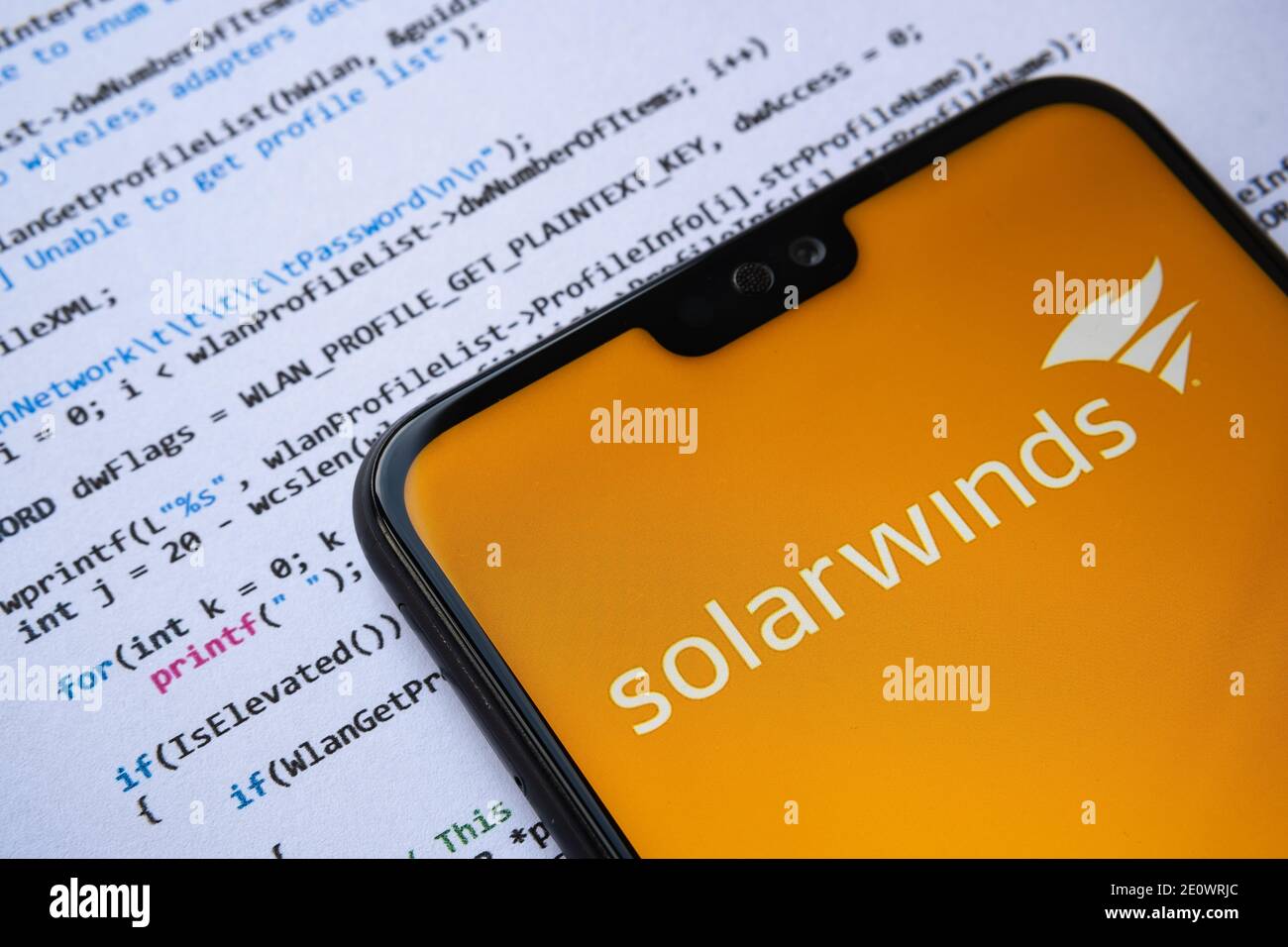 Stafford, Royaume-Uni - 2 janvier 2021: Logo SolarWinds vu sur l'écran du smartphone, avec un simple code d'attaque C sur le fond papier. Banque D'Images