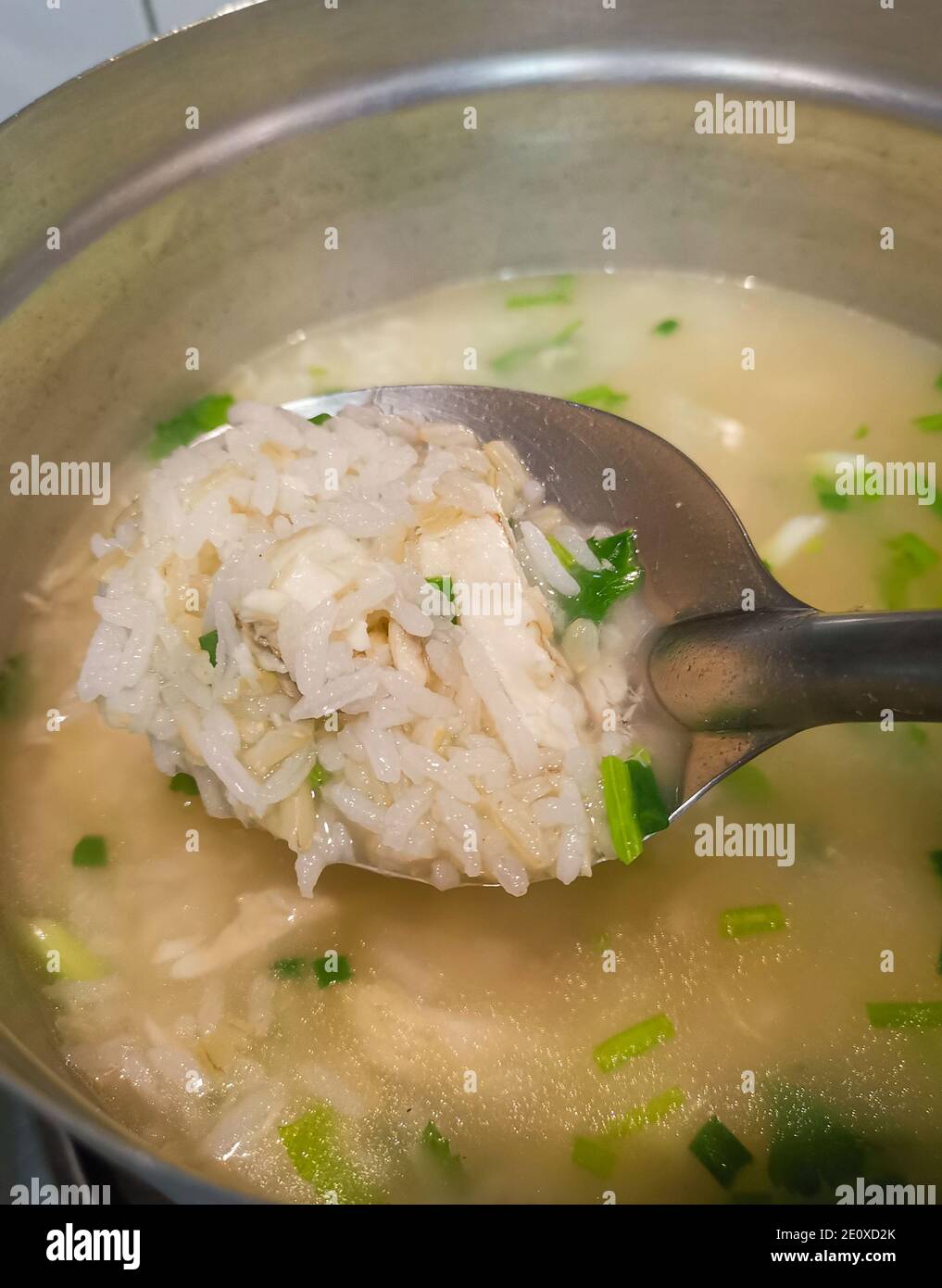 Porridge de poulet avec oignon de printemps dans une casserole de métal. Le processus de fabrication de la nourriture de petit déjeuner thaï Banque D'Images