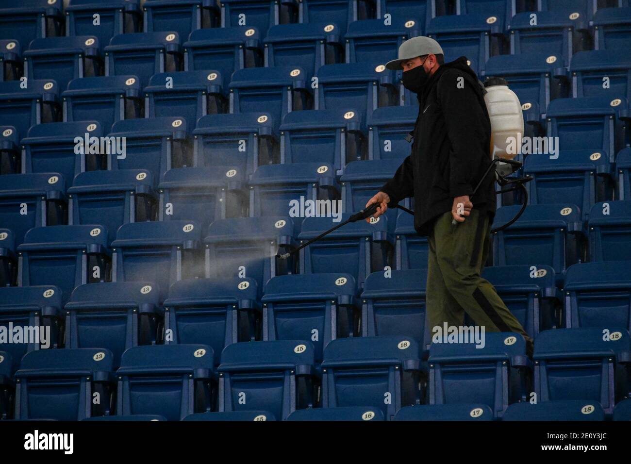 Un homme vaporise du désinfectant dans les stands entre les matchs de football pour aider à prévenir la propagation du nouveau coronavirus, le lundi 28 décembre 2020 à Bullhe Banque D'Images