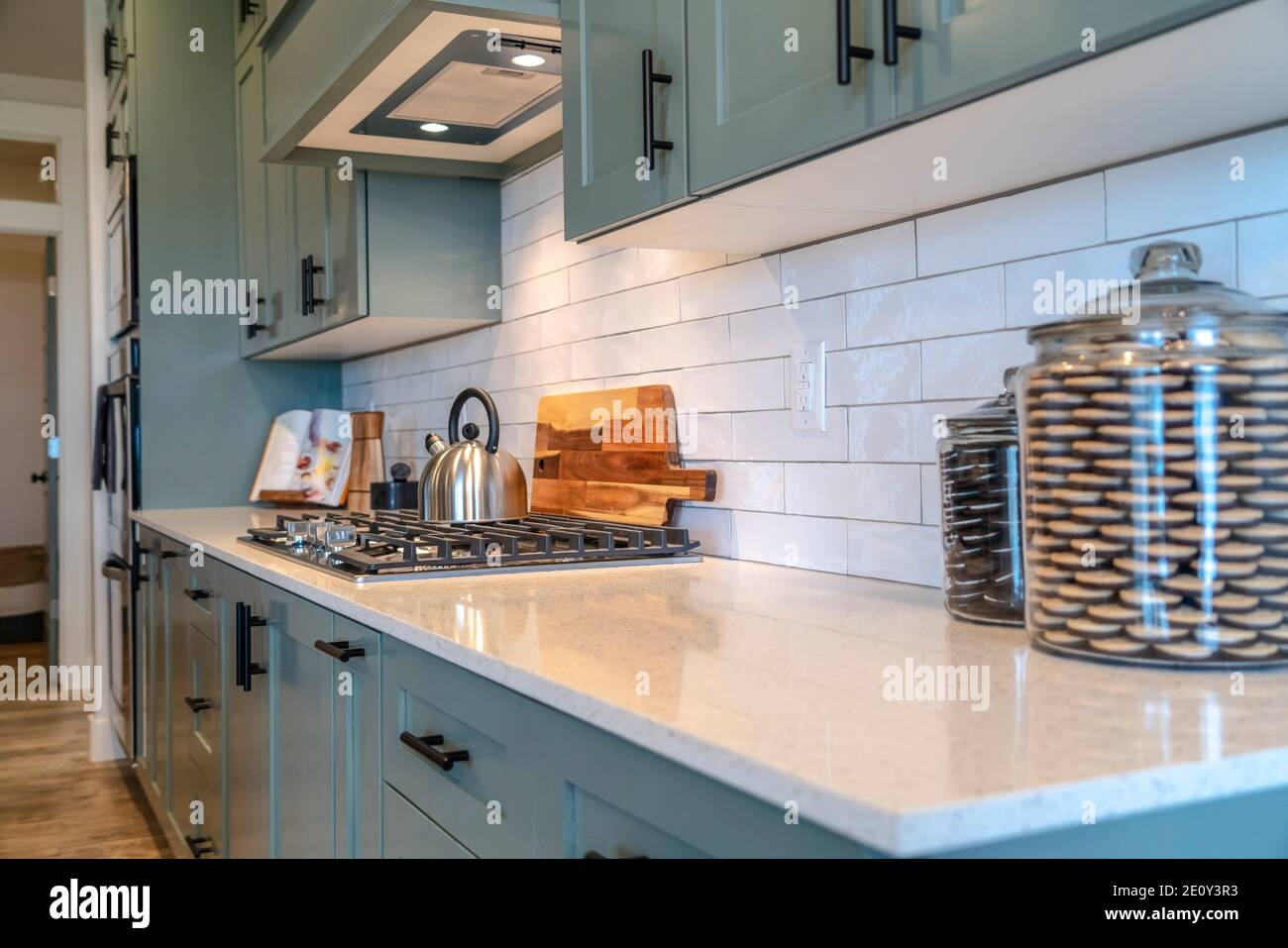 Bouilloire sur une table de cuisson fixée sur un comptoir blanc avec des petits pots cuisine intérieure Banque D'Images