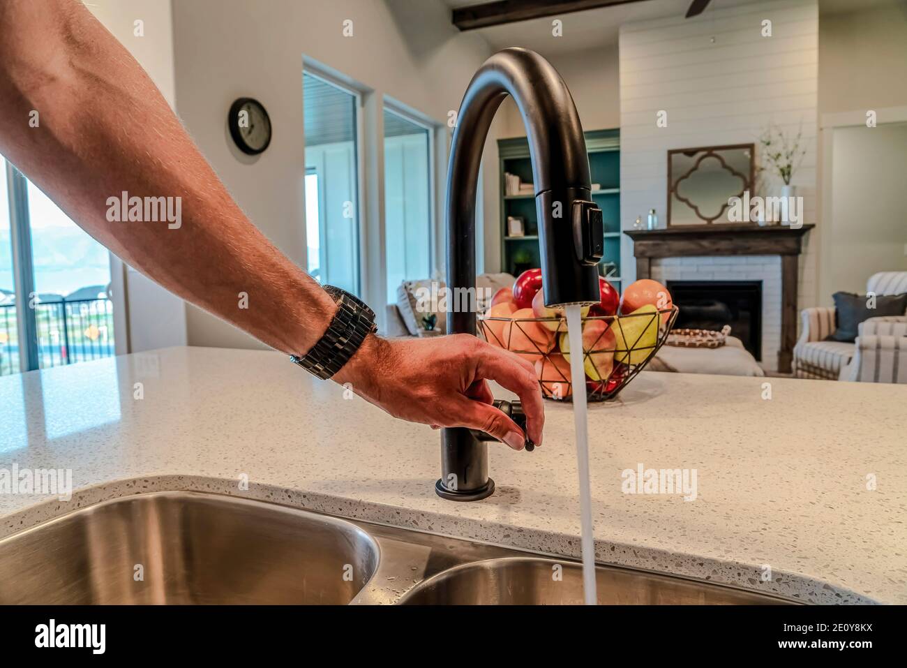 Main mâle sur le levier du robinet avec l'eau fron bec verseur noir dans la  cuisine Photo Stock - Alamy