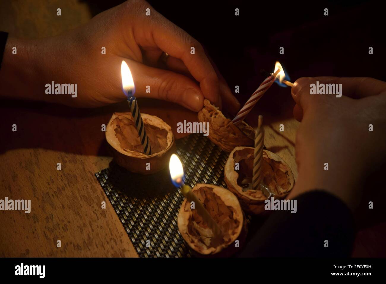 Les mains éclaient les bougies à l'intérieur de la coquille de noyer - la veille de Noël tchèque est liée à plusieurs traditions, laisser flotter la coquille de noyer est l'un d'entre eux. Banque D'Images