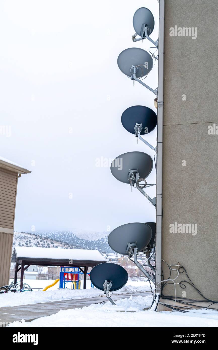 La télévision par satellite sert des plats sur le mur extérieur d'un bâtiment dans un paysage enneigé Banque D'Images
