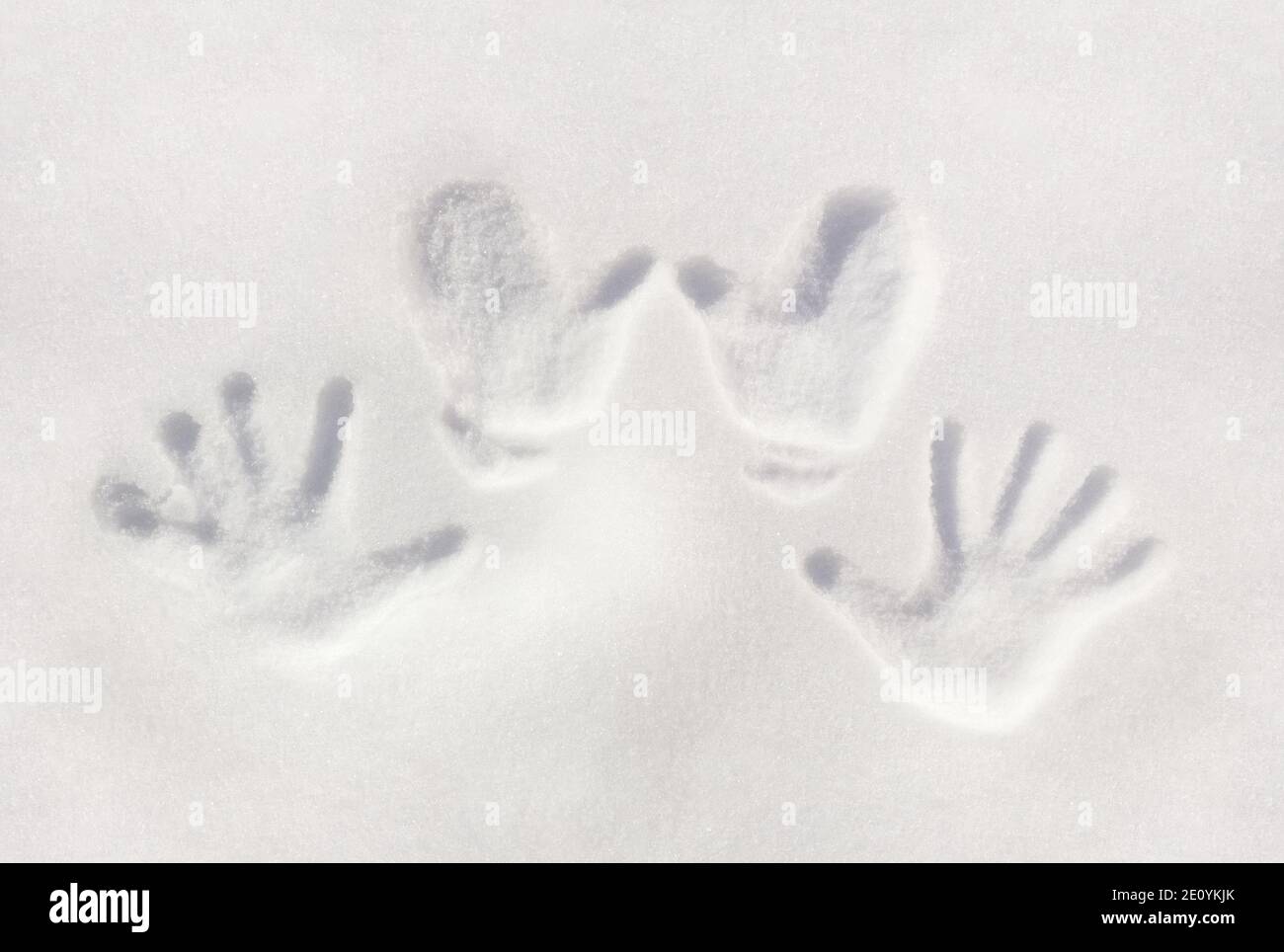 Arrière-plan hivernal avec des empreintes de palmiers des mains humaines sur une surface de neige claire. Banque D'Images