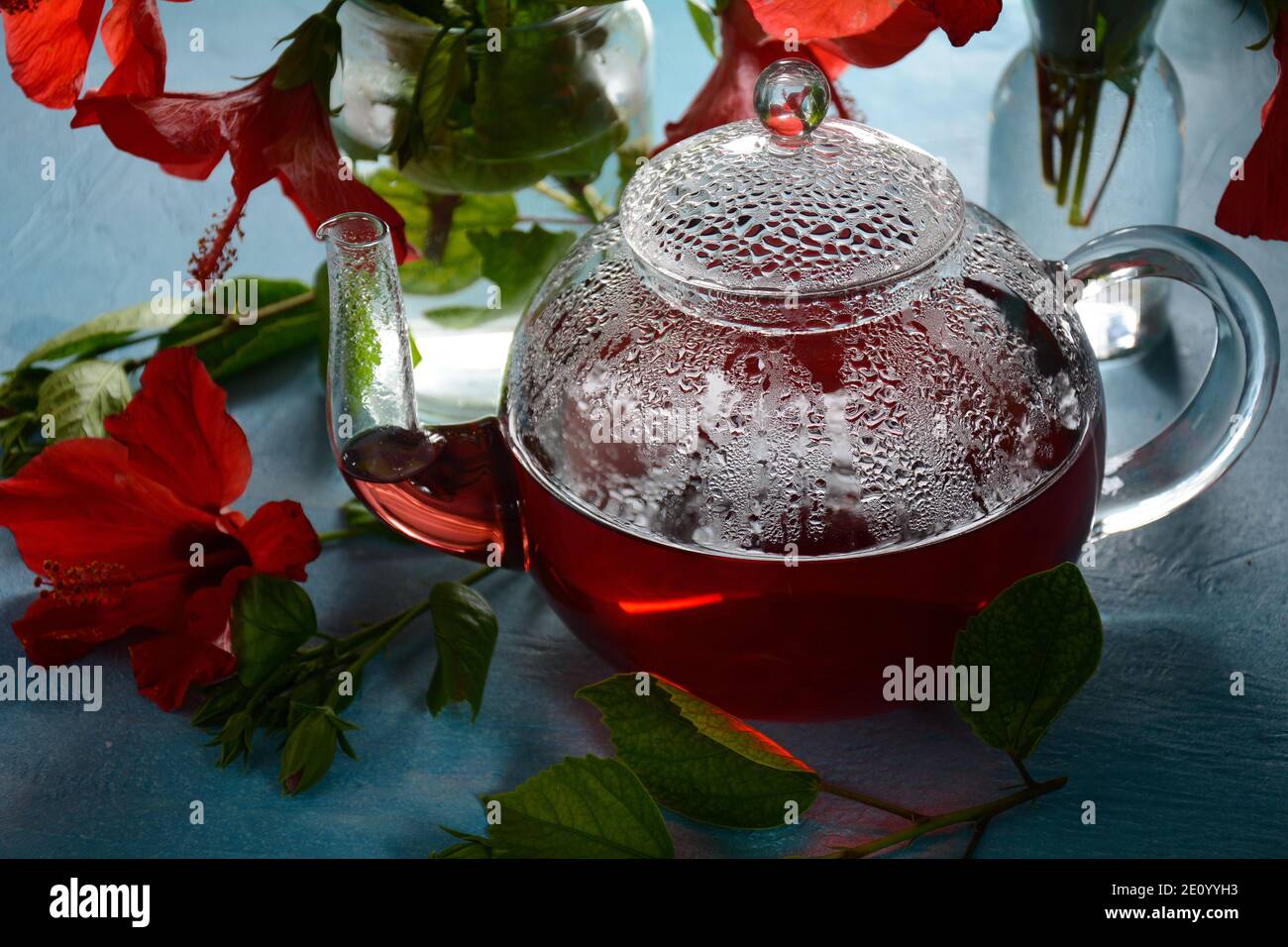 Thé Hibiscus dans un verre transparent théière, et fleur Banque D'Images