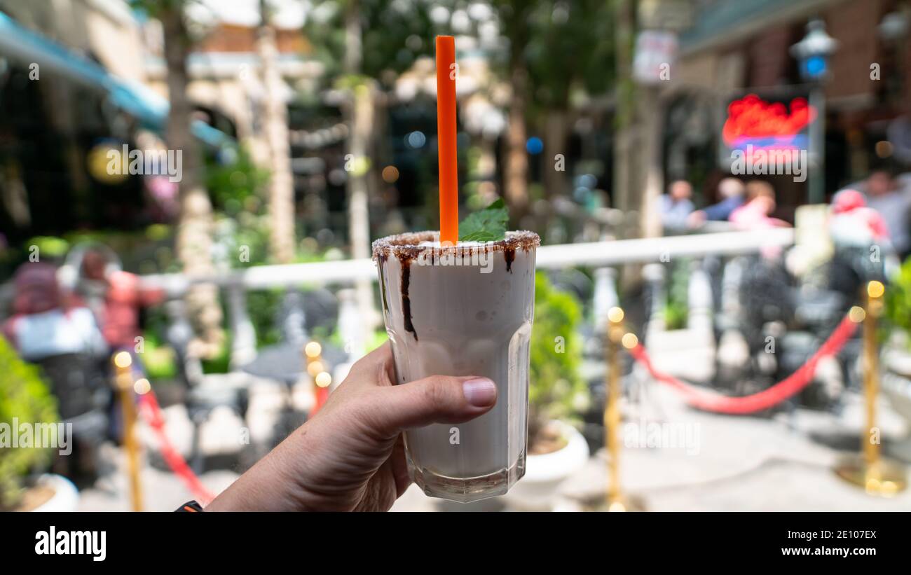 Main tenant un verre de milkshake au chocolat sur fond flou, détendez-vous le week-end, concept de boisson d'été. Banque D'Images