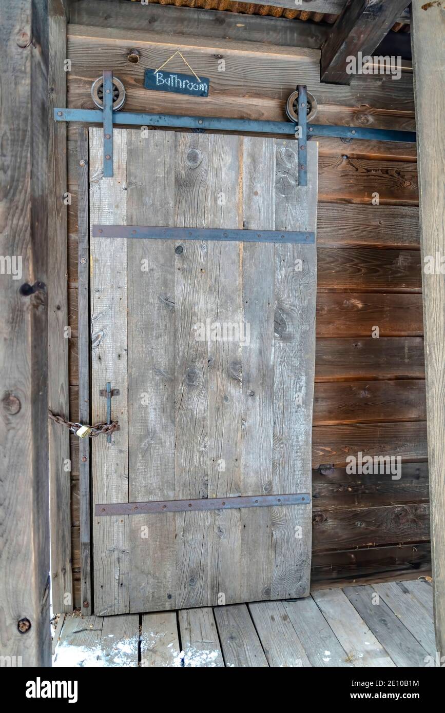 Porte coulissante en bois verrouillée d'une ancienne salle de bains  extérieure avec chaîne et cadenas Photo Stock - Alamy