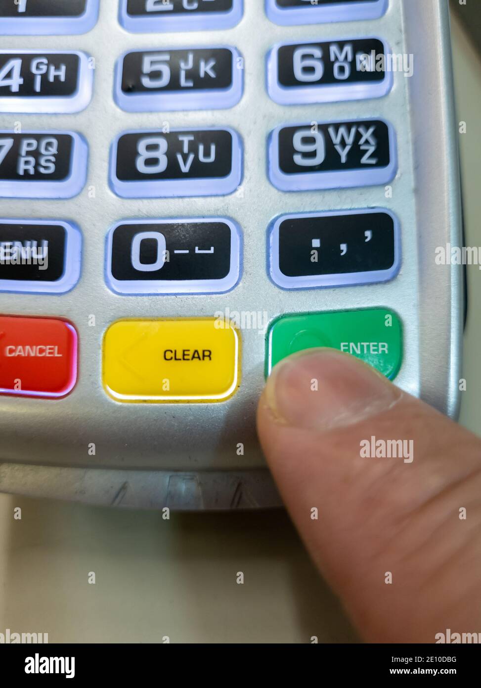 Une personne utilisant un doigt en appuyant sur le bouton ENTER d'un lecteur de carte pour effectuer un paiement. Banque D'Images