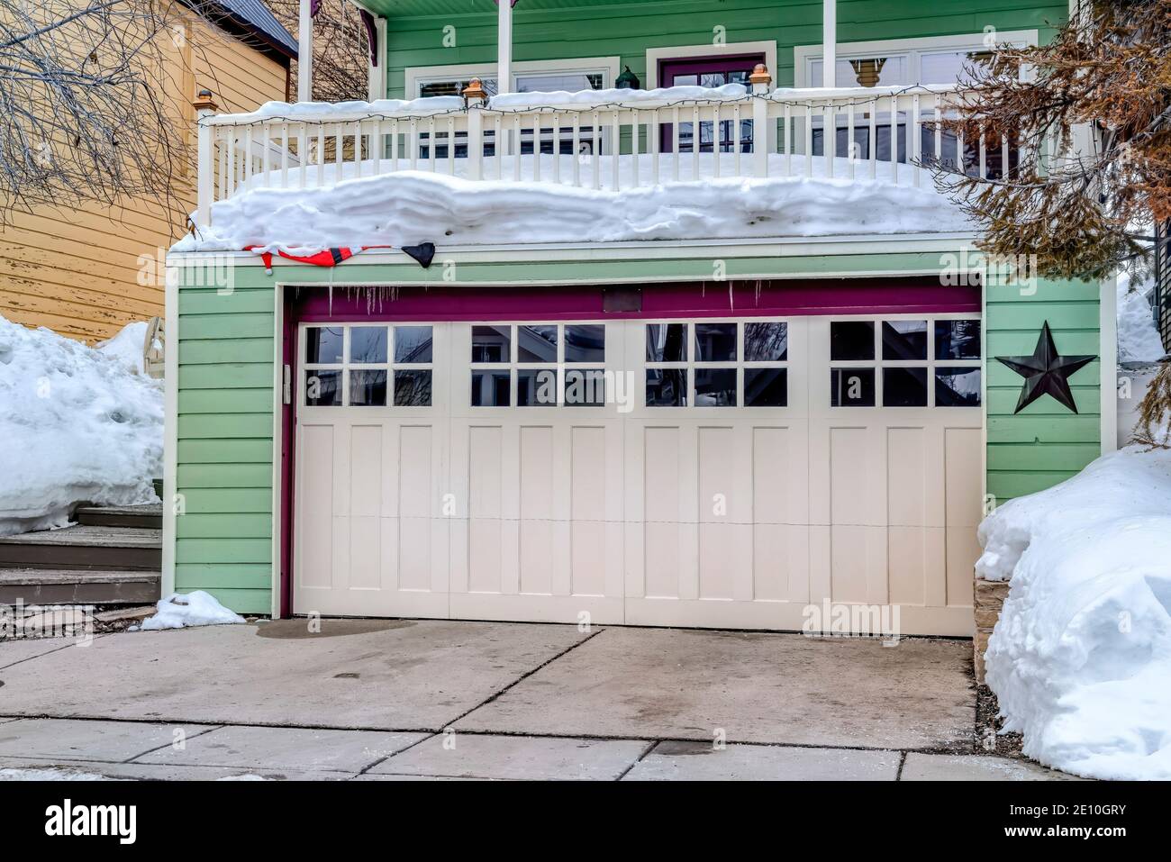 Garage pour deux voitures avec vitres sur porte blanche sous neigé dans le balcon de la maison Banque D'Images