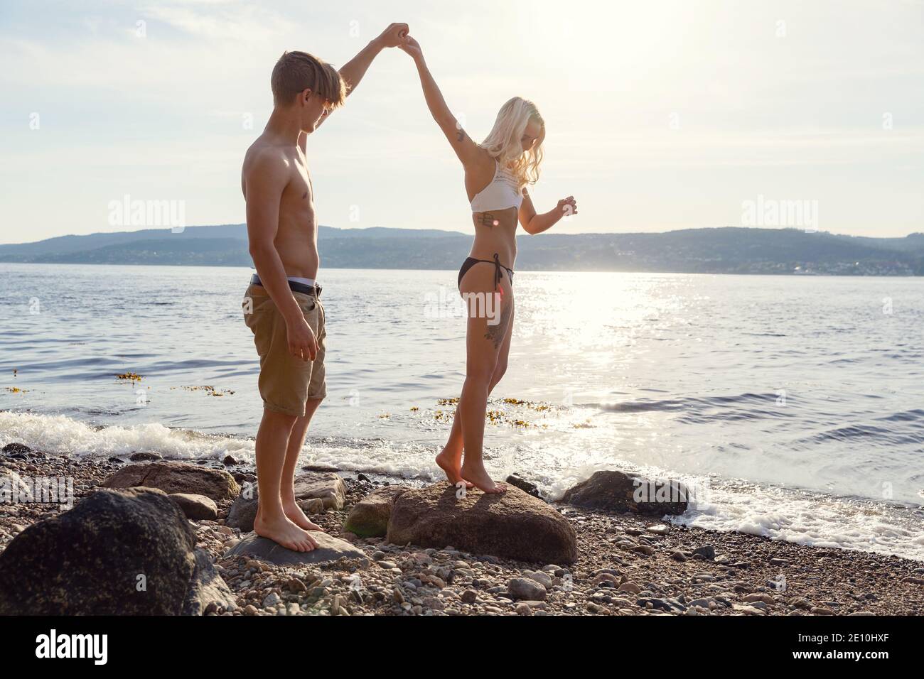 Dans l'amour couple holding hands at the beach contre sun Banque D'Images