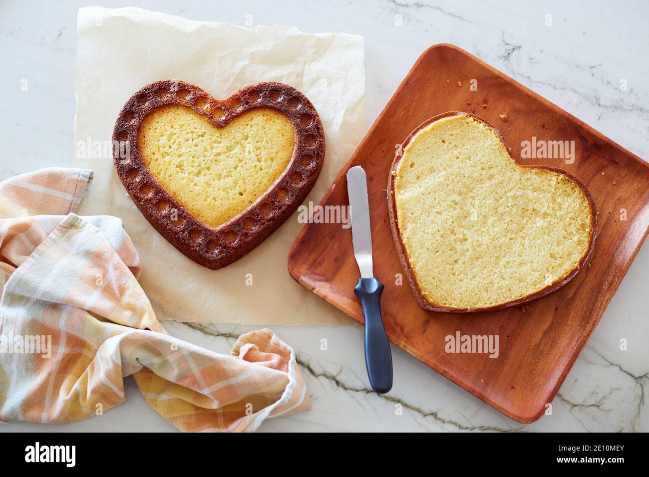 Couches de gâteau en forme de coeur et papier parchemin sur une surface en marbre avec Serviette Banque D'Images
