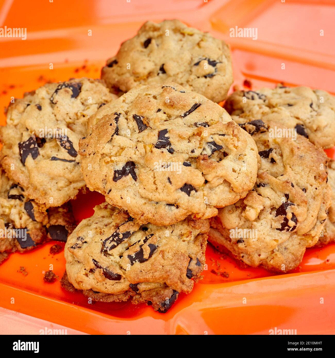 Groupe de biscuits aux pépites de chocolat sur un plat en plastique orange, culture carrée Banque D'Images