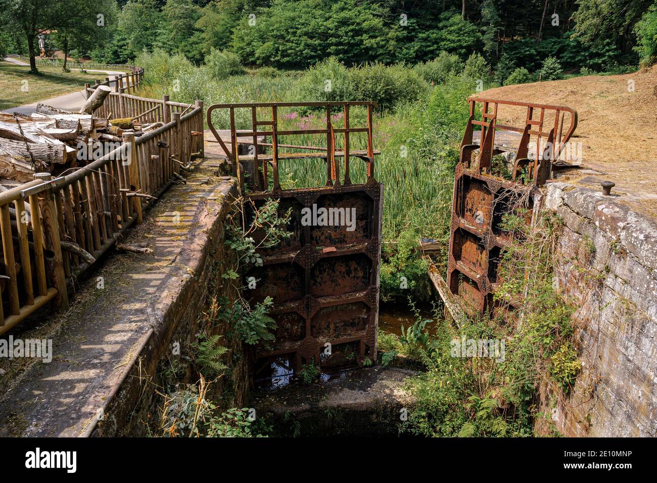 France. Un canal abandonné dans la région de Saverne, une ancienne porte-écluse rouillée reste attachée aux parois du bassin. Banque D'Images