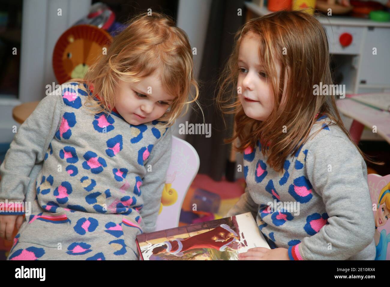 Une fille de 4 ans lisant un livre à sa petite sœur. Banque D'Images
