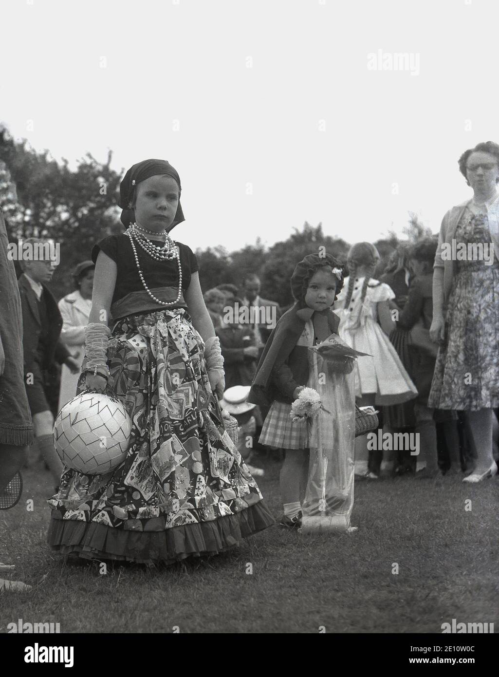 Années 1950, historique, deux petites filles vêtues de costumes pour un défilé à la Rose Queen Celebrations, Farnworth, Angleterre, Royaume-Uni. Banque D'Images