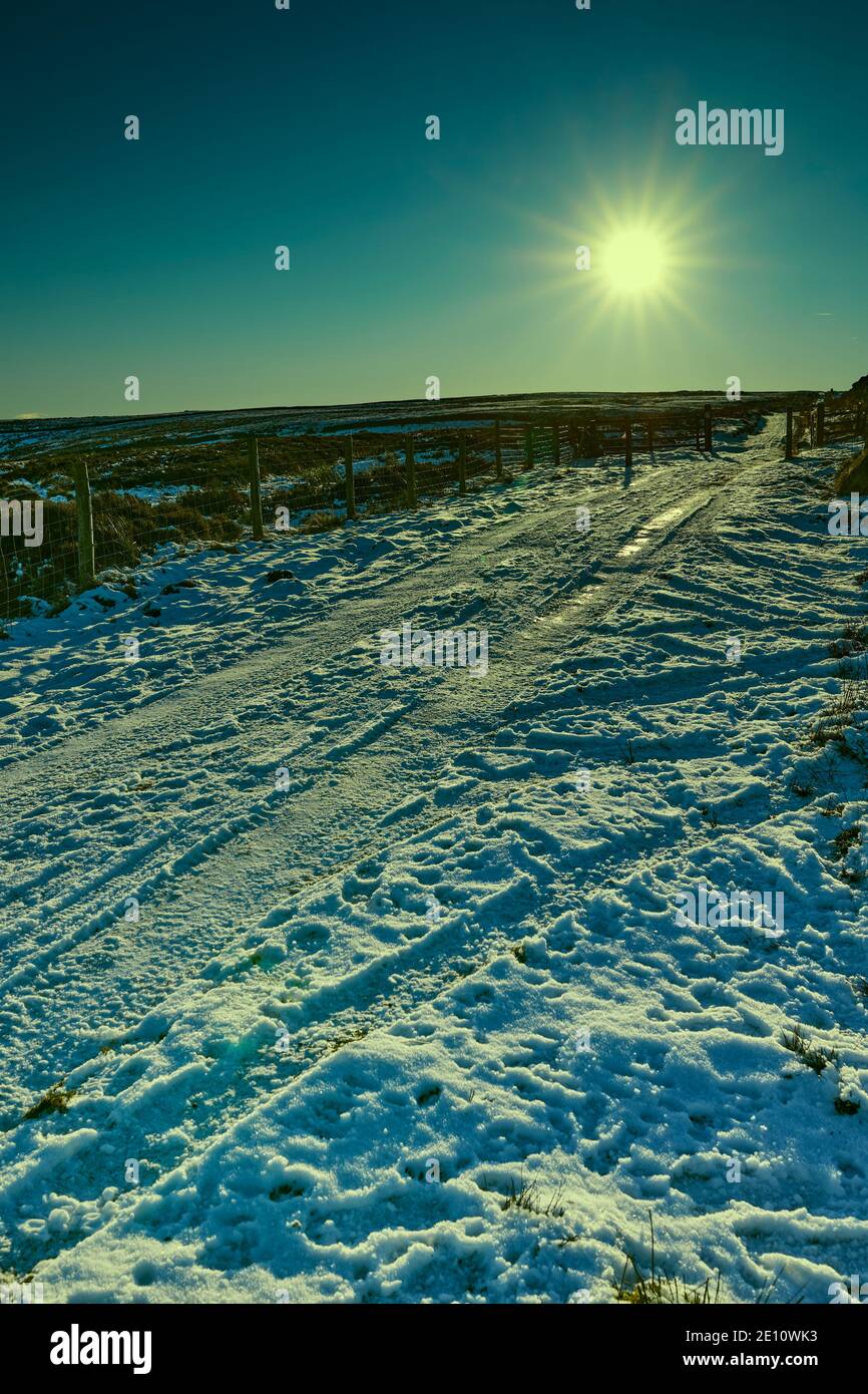En fin d'après-midi, et un faible soleil illumine une piste de moorland enneigée dans le Yorkshire Banque D'Images