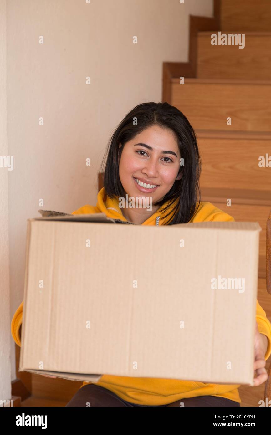 belle femme latine dans son nouvel appartement assis avec un boîte en carton à côté de quelques gradins en bois l'été jour Banque D'Images