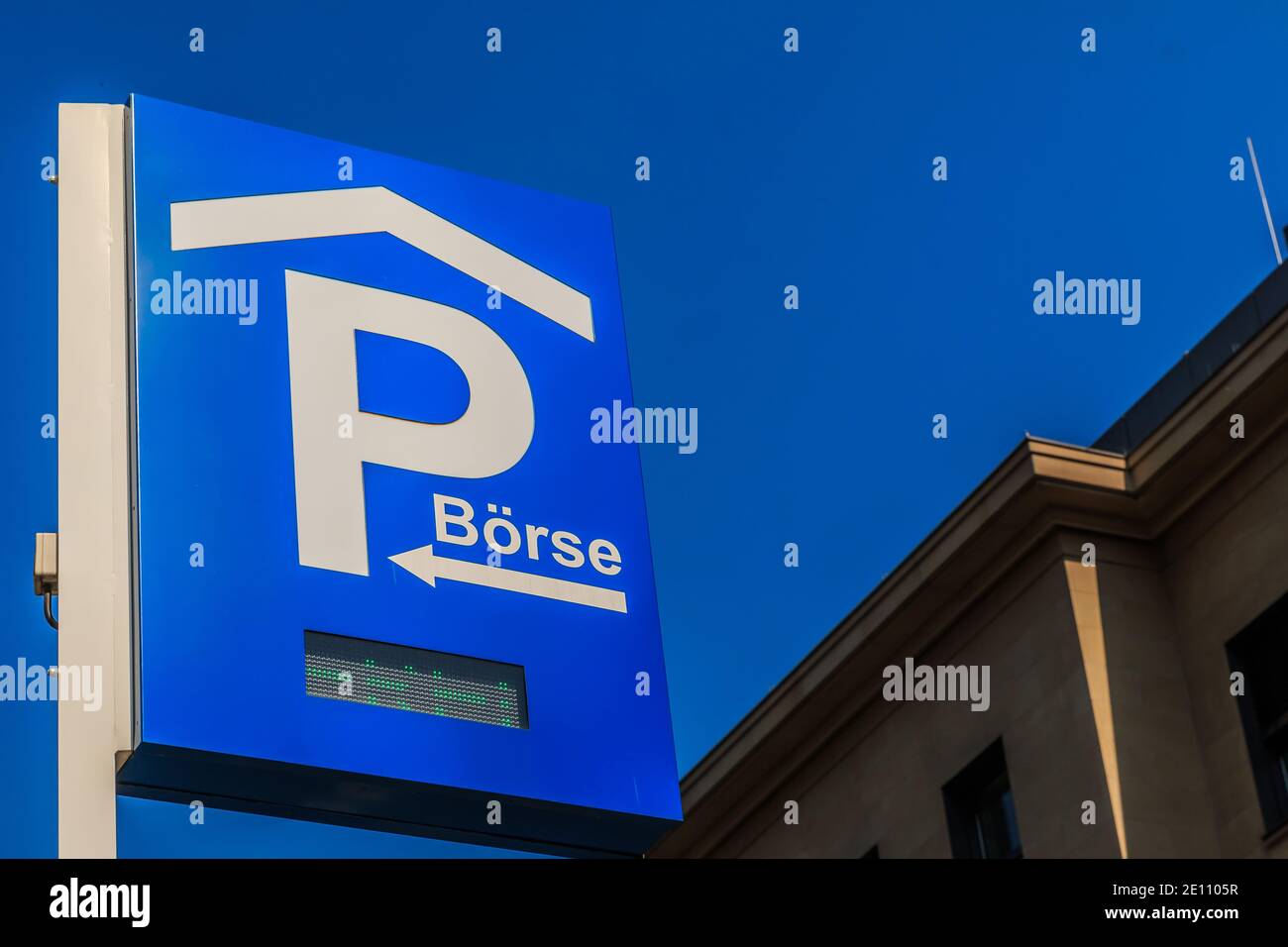 Signalisation routière sur le parking avec inscription LED. Panneau de stationnement bleu de la Bourse de Francfort sur un poteau. Ciel bleu avec façade de maison en arrière-plan Banque D'Images