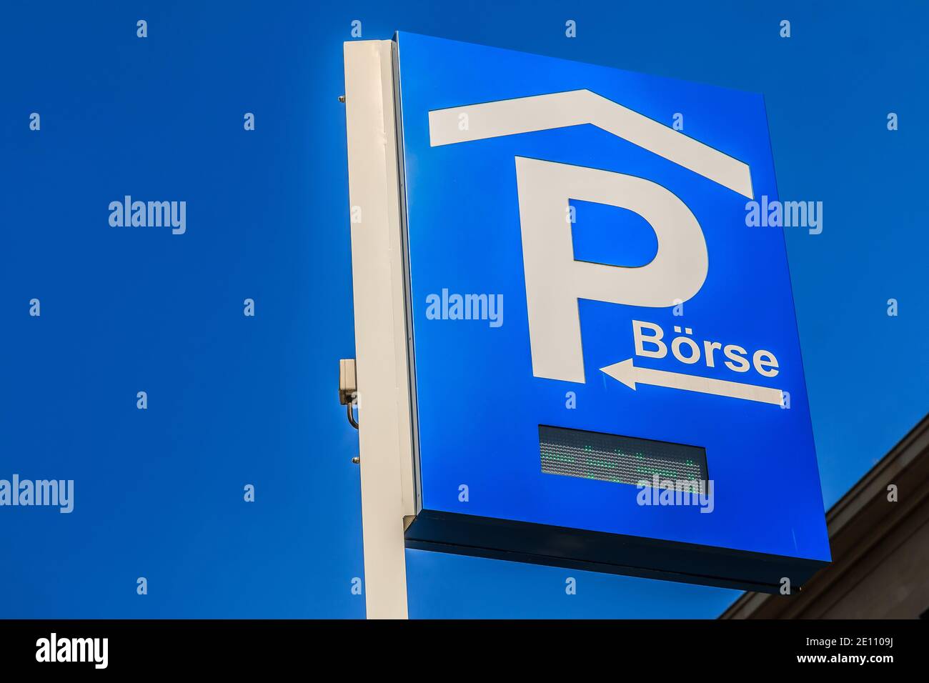 Signez le stationnement avec un éclairage à DEL. Panneau de stationnement bleu de la Bourse de Francfort sur un poteau. Panneau de signalisation sous ciel bleu avec façade de la maison à l'arrière Banque D'Images