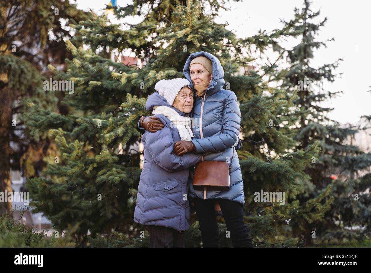 Concept de famille heureuse, vieillesse, émotions, soins aux aînés en âge de retraite. Grand-mère senior active et fille adulte embrassant dehors en hiver agai Banque D'Images
