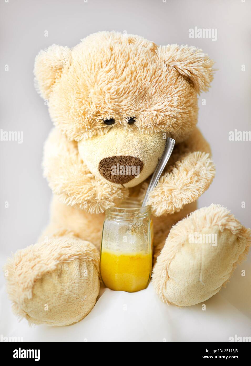 L'ours en peluche est assis et mange du miel Photo Stock - Alamy