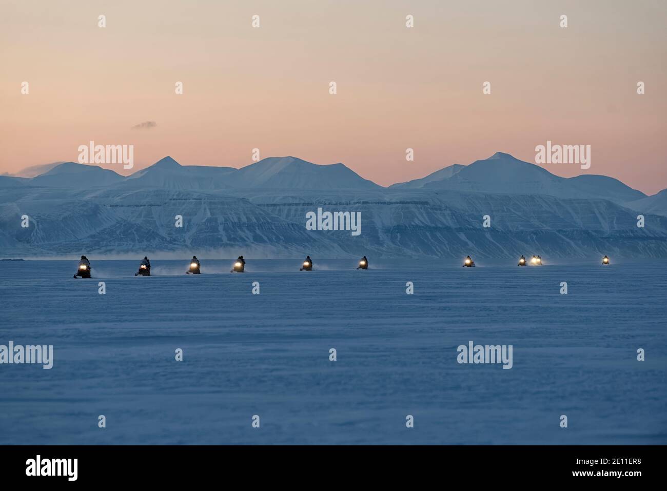 Saison sombre sur Svalbard. Au crépuscule, en février, les motoneiges se trouvant dans une rangée sur le Tempelfjorden gelé, Spitsbergen, Svalbard, Norvège Banque D'Images