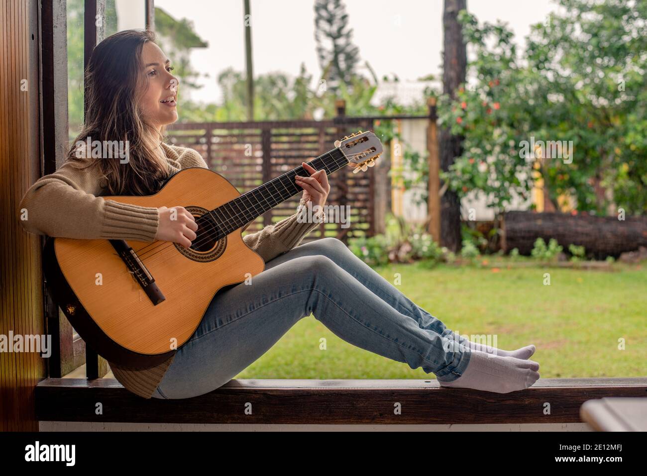 Femme jouant de la guitare à la fenêtre Photo Stock Alamy