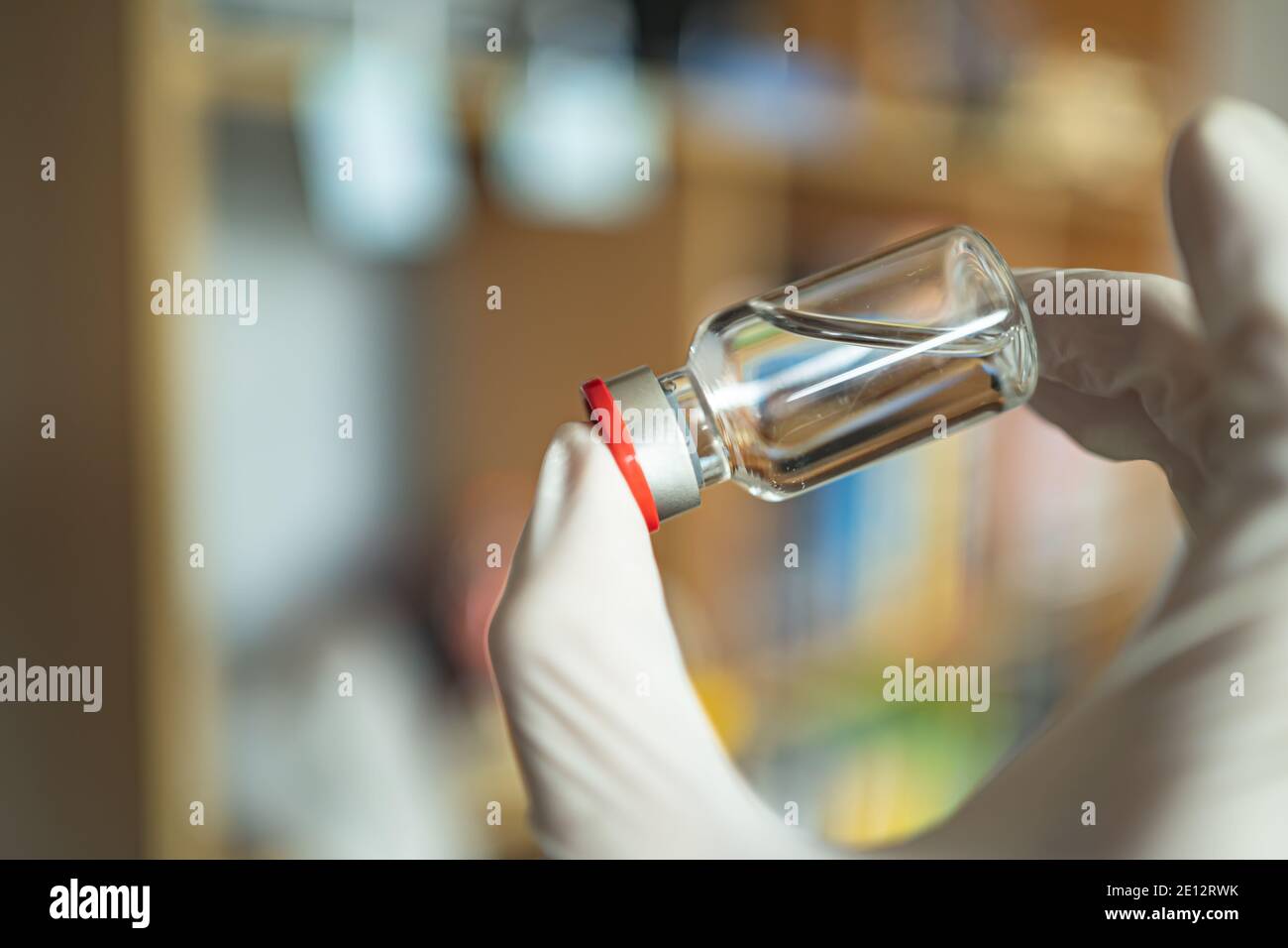 Une bouteille de vaccin dans une main avec un gant Banque D'Images