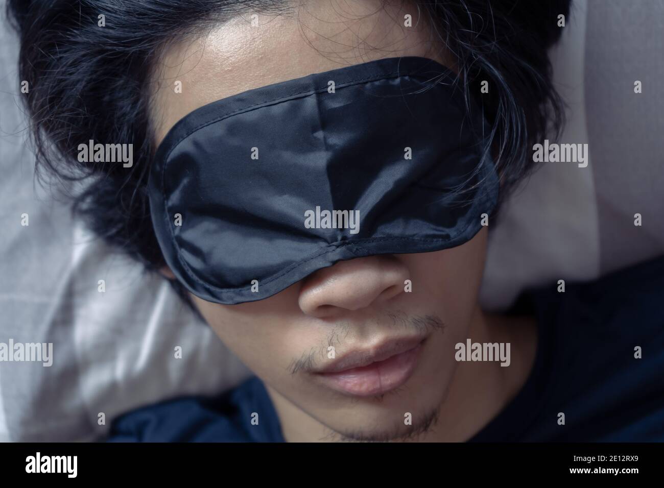 Un homme dormant avec un masque de sommeil Banque D'Images