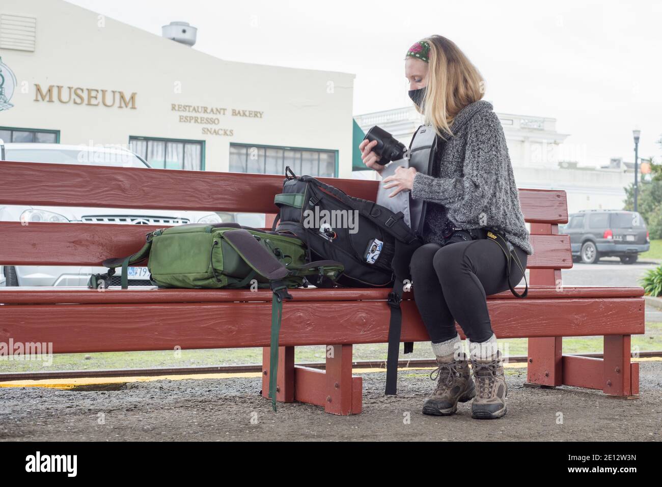 Une photographe qui change ses objectifs avant de se rendre dans un musée derrière elle à fort Bragg, en Californie. Banque D'Images