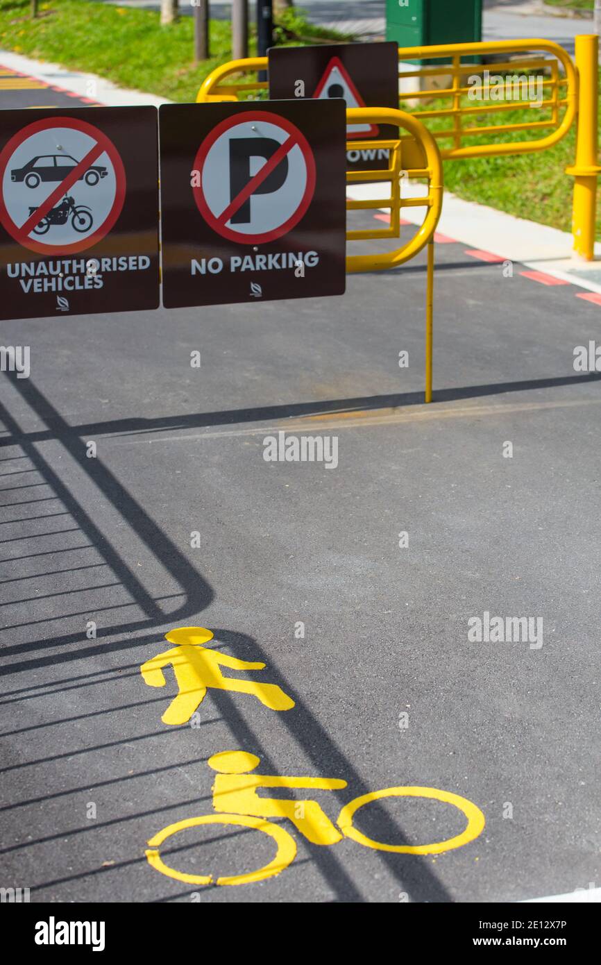 Scène verticale de barrières jaunes avec panneaux et marquages sans entrée attachés sur le tarmac à un connecteur de parc, Singapour. Banque D'Images