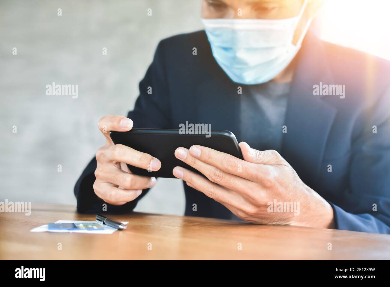 Homme d'affaires sous masque en utilisant un smartphone mobile pour travailler en ligne concentrez-vous Banque D'Images