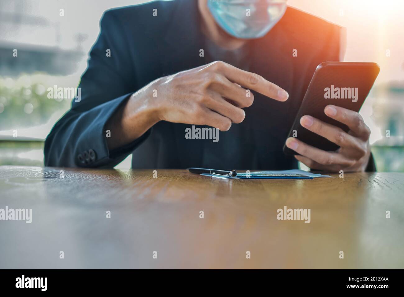 Homme d'affaires sous masque en utilisant un smartphone mobile pour travailler en ligne concentrez-vous Banque D'Images