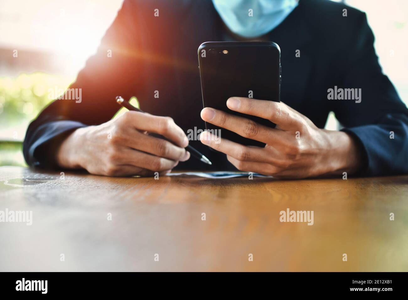 Homme d'affaires sous masque en utilisant un smartphone mobile pour travailler en ligne concentrez-vous Banque D'Images