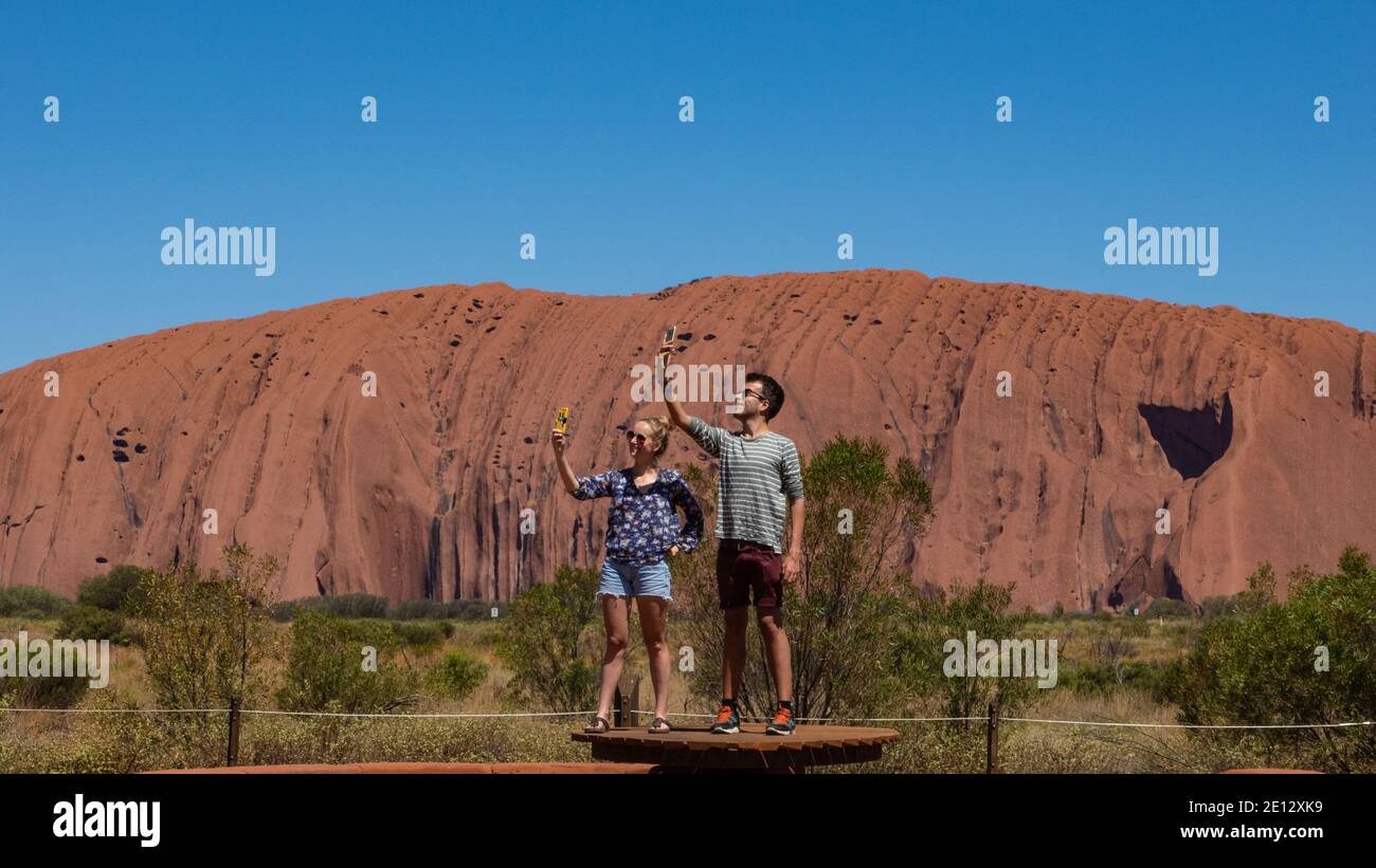 Uluru Australie centrale. Deux touristes prennent des selfies au monolithe de grès Uluru à Uluru - parc national de Kata Tjuta territoire du Nord, Banque D'Images