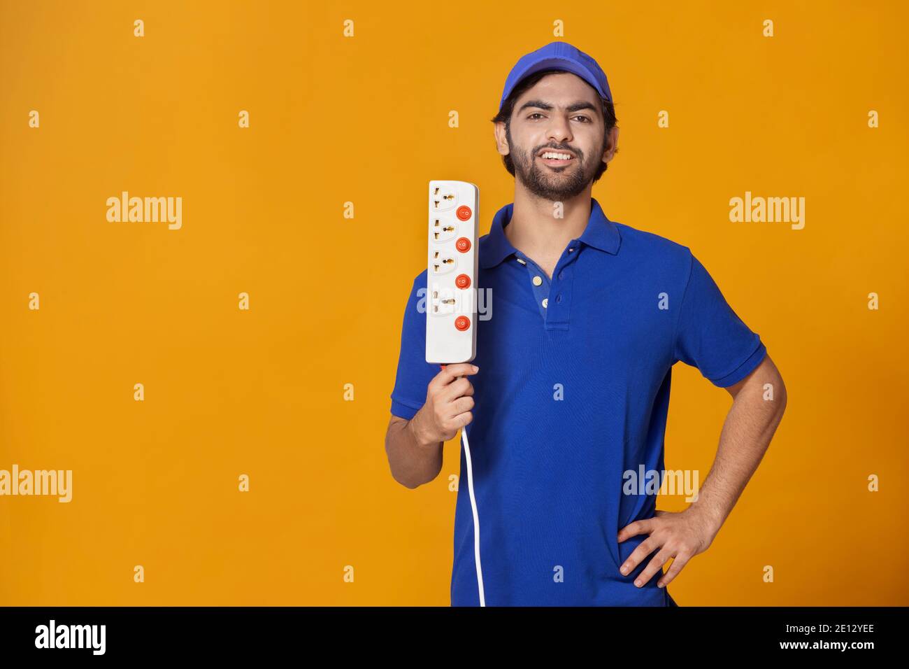 UN ÉLECTRICIEN TENANT UNE CARTE D'EXTENSION ET SOURIANT À LA CAMÉRA Banque D'Images