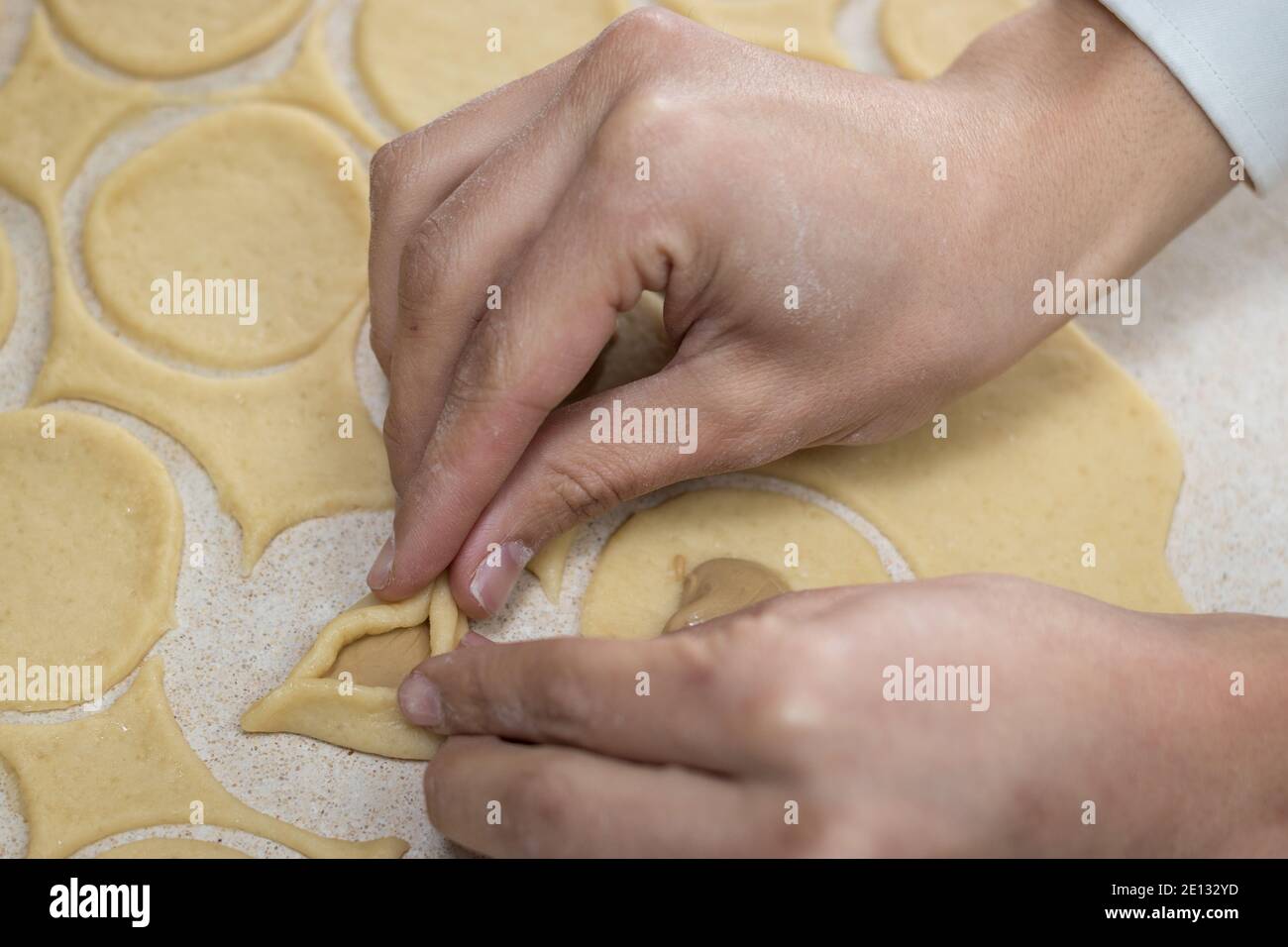 Hamantaschen. (Ozenei haman) pâte triangulaire à base de pâte croustillante, farcie de pavot, d'halva ou de chocolat. Pour les vacances juives de Purim. Mains dans Banque D'Images