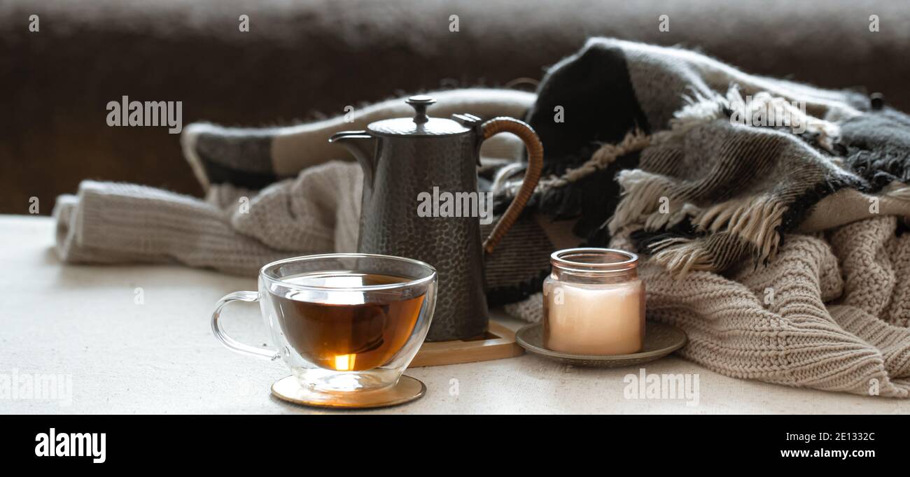 Encore la vie avec une tasse de thé, une théière, une bougie dans un chandelier et des choses tricotées gros plan. Banque D'Images