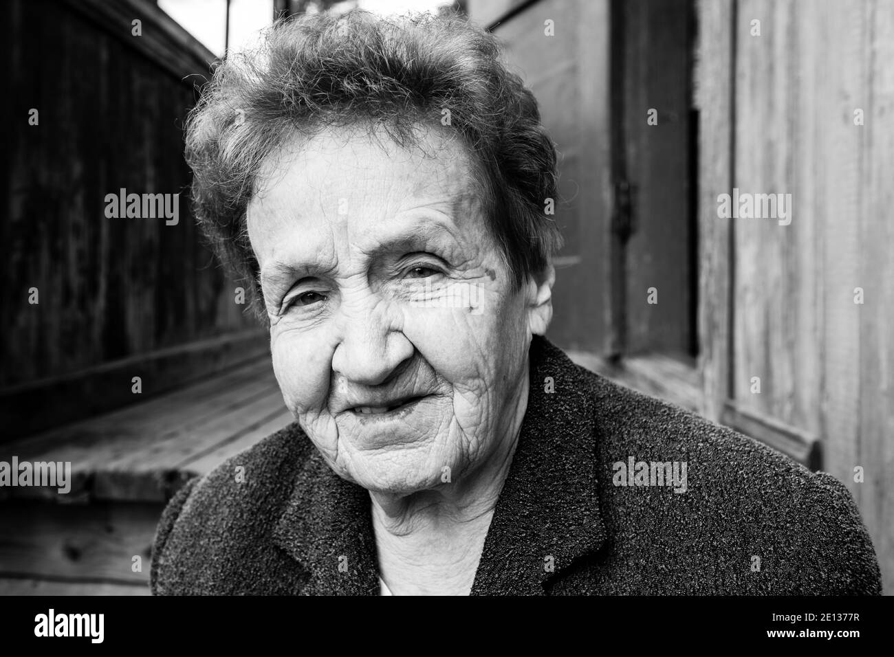 Portrait de la vieille femme près d'une maison rurale. Photo en noir et blanc. Banque D'Images