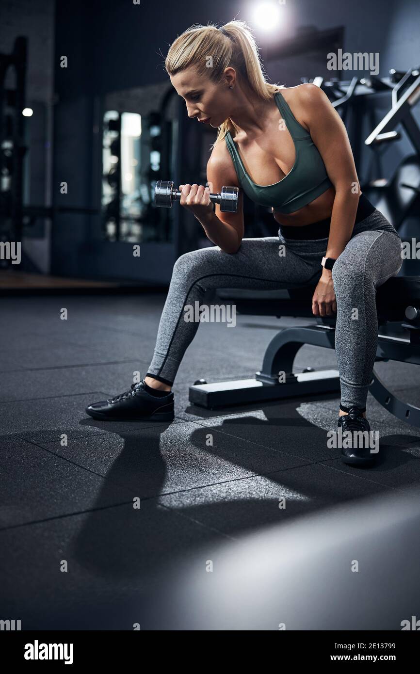 Une sportswoman focalisée sur une machine d'exercice qui tire son bras Banque D'Images