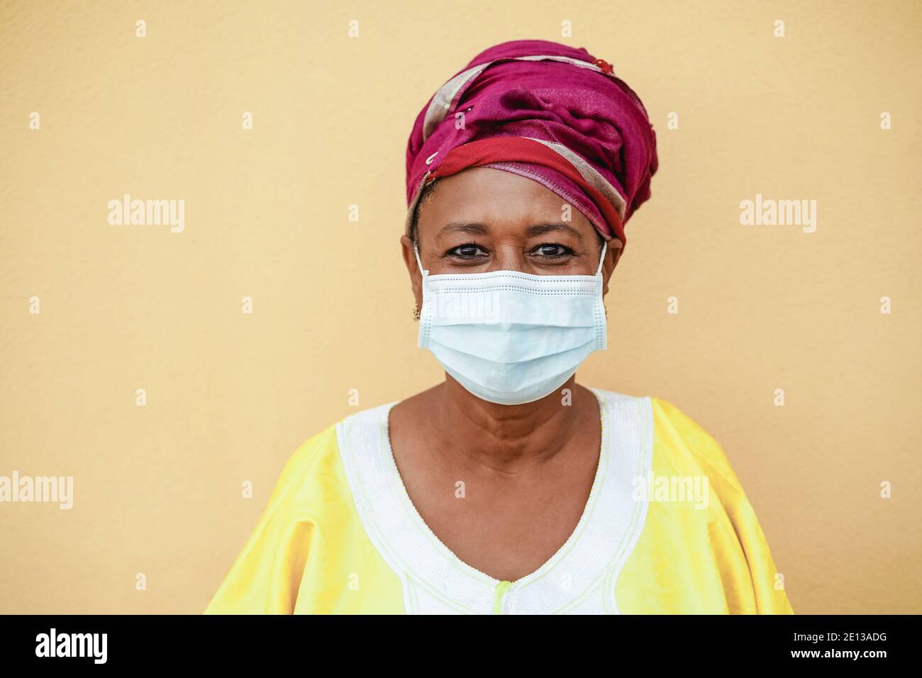 Heureuse femme noire senior avec masque facial portant un traditionnel africain Habillage - se concentrer sur le visage Banque D'Images